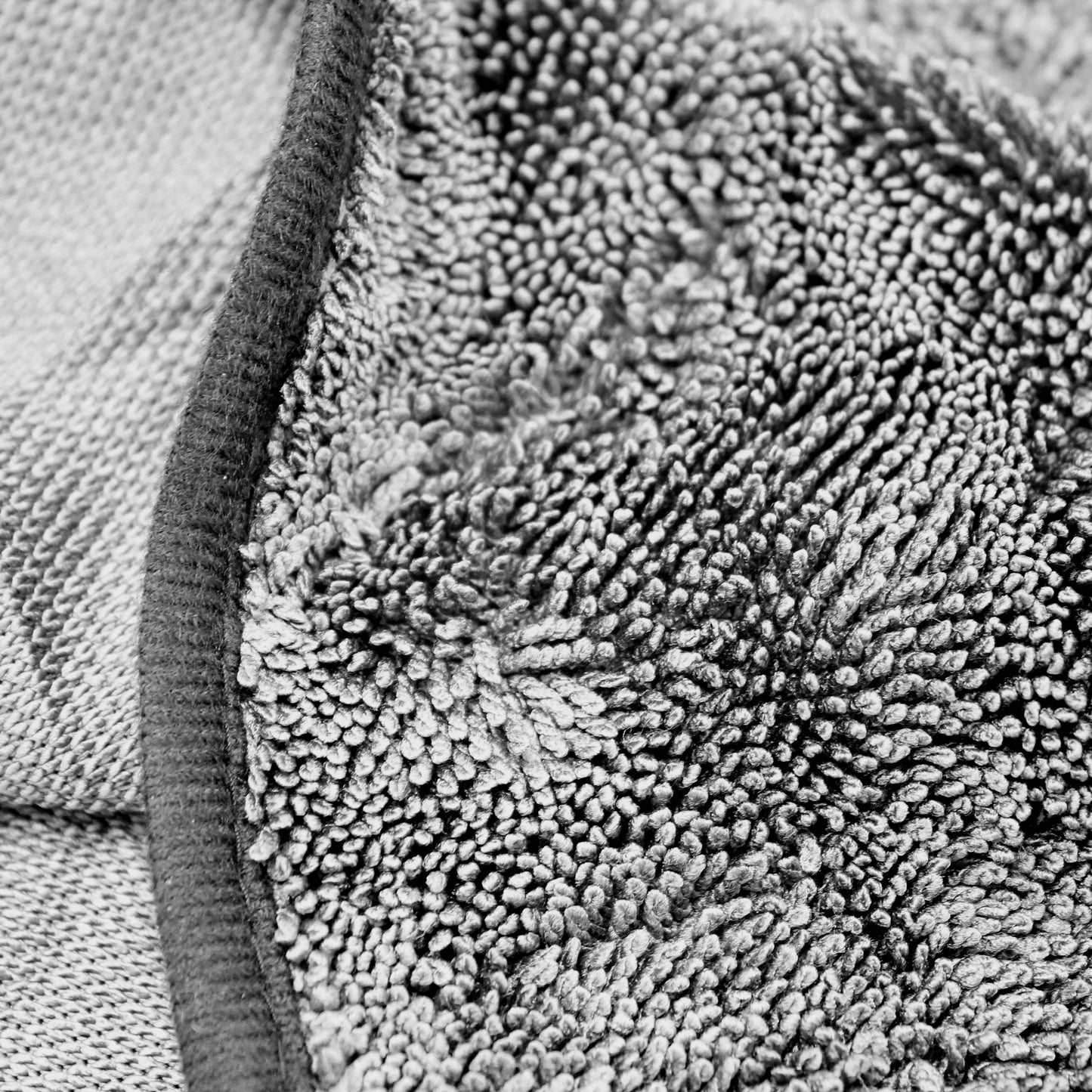 Close up of the dense twisted loop microfibre pile and edge binding of the charcoal grey dog drying towel