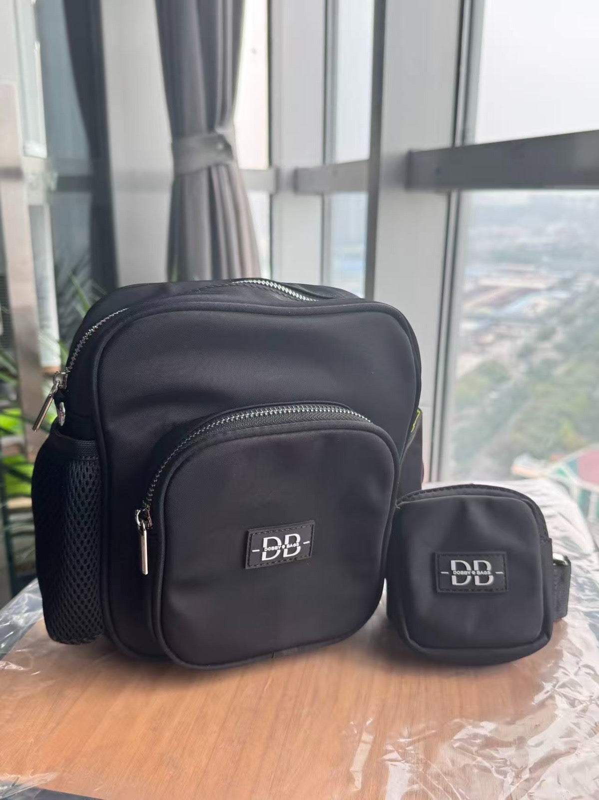 The OG black dog walking bag beside its matching treat pouch, with the stretch mesh bottle pocket in view