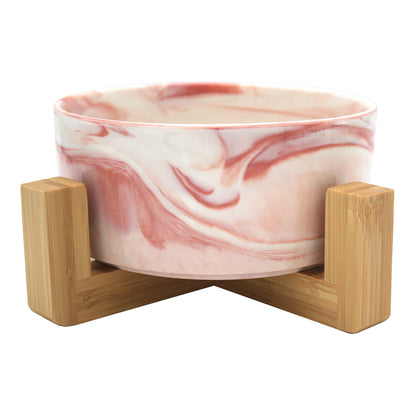 Duke & Milo raised ceramic dog bowl in marble pink, sitting in its bamboo stand