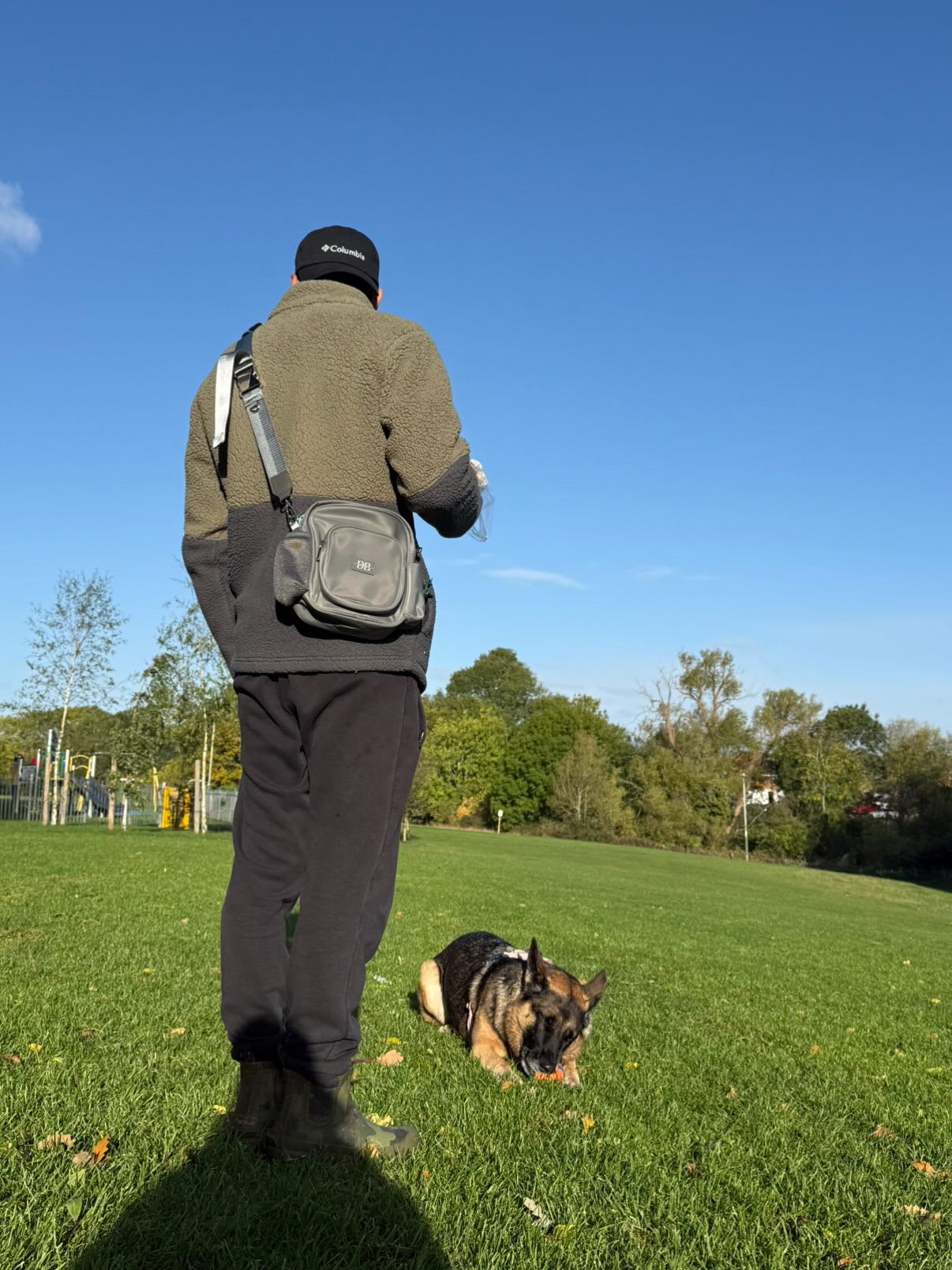 A man wearing The PEBBLE grey bag crossbody on a walk with his dog