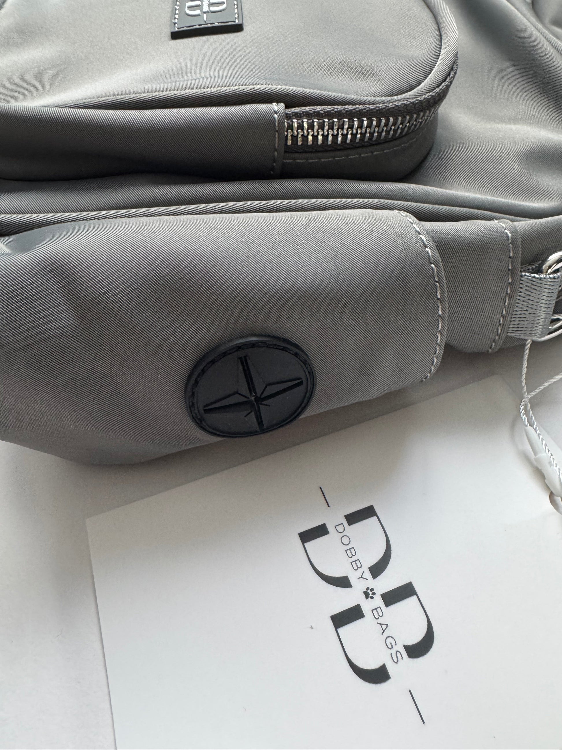 Close up of the grey nylon side panel on The PEBBLE, showing the waste bag dispenser opening