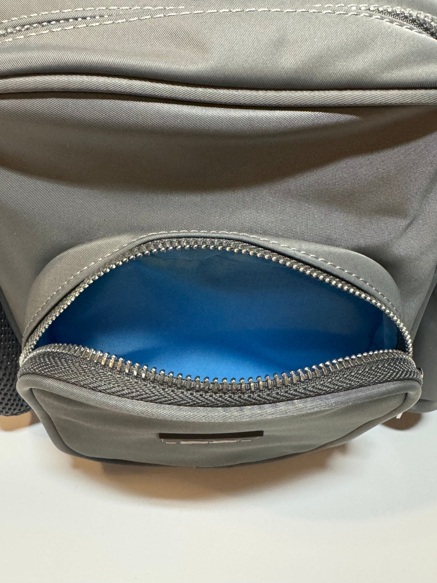 Close up of the front pocket on The PEBBLE, unzipped to show the bright blue lining