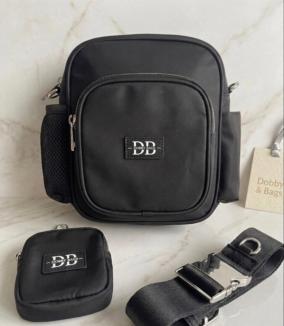 The OG black dog walking bag with its matching treat pouch and adjustable strap on a marble surface