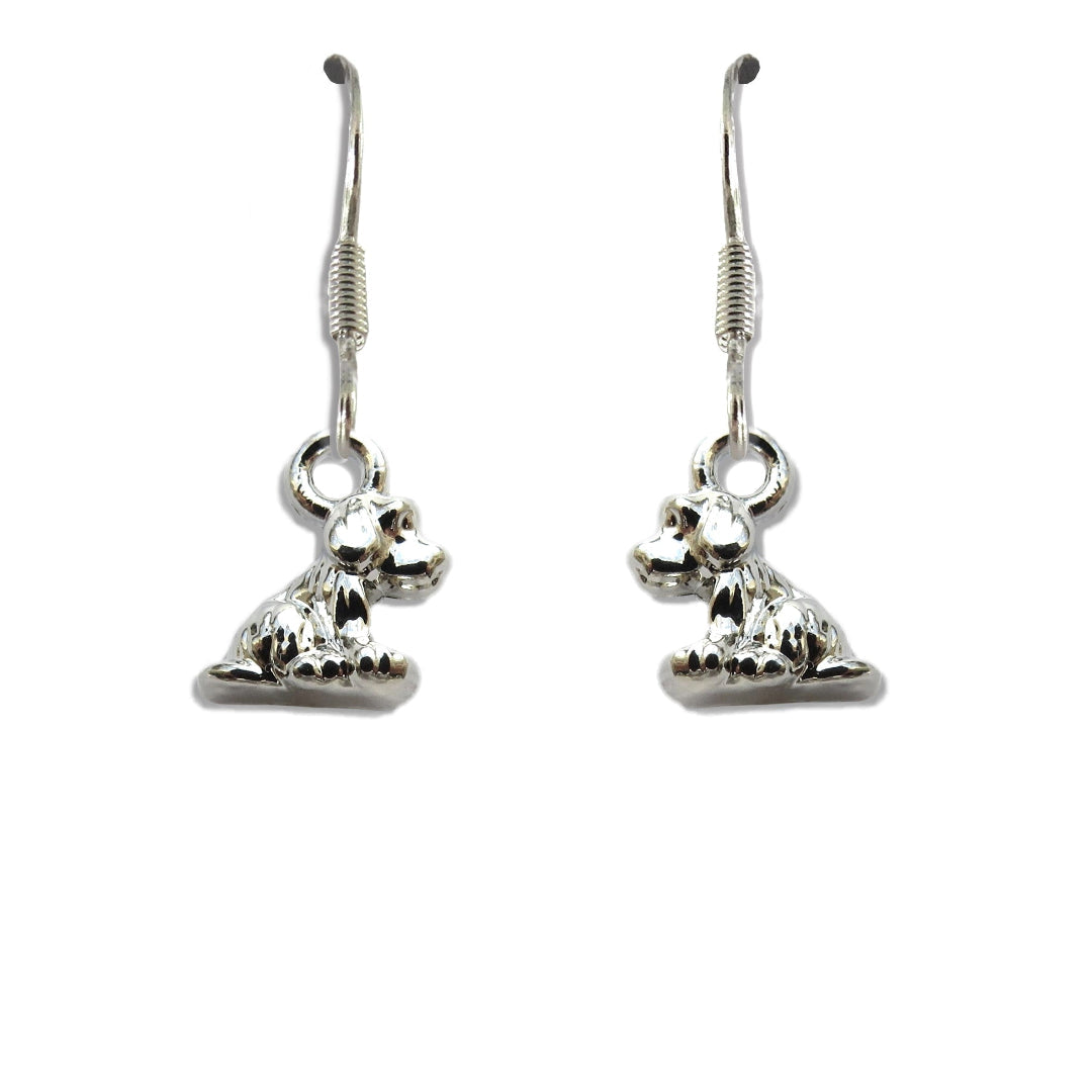 Pair of silver plated little dog drop earrings on fishhook wires, each charm shaped as a seated puppy, on a plain white background.