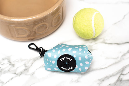 Blue spotted poo bag holder beside a dog bowl and a tennis ball