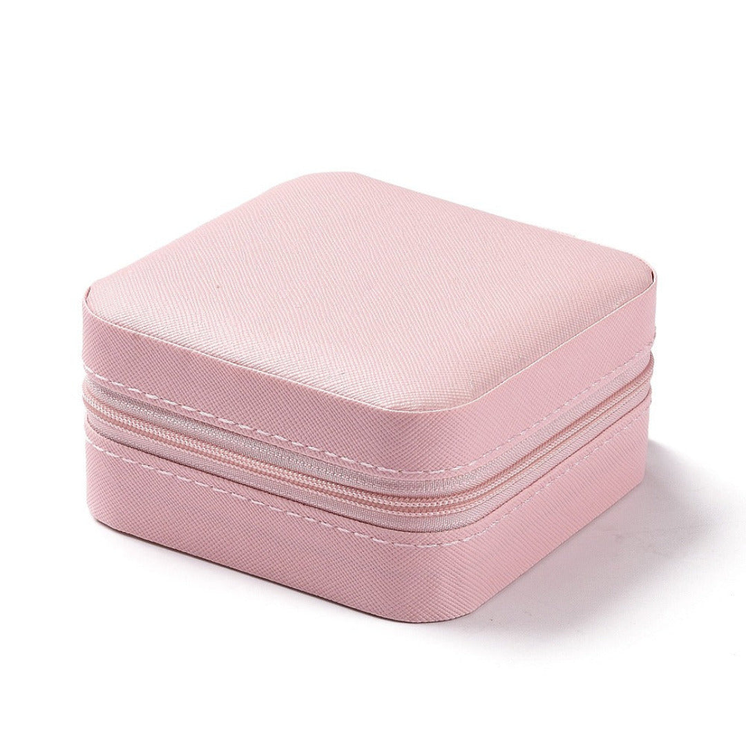 Pink zip up travel jewellery box closed, shown on a plain white background.