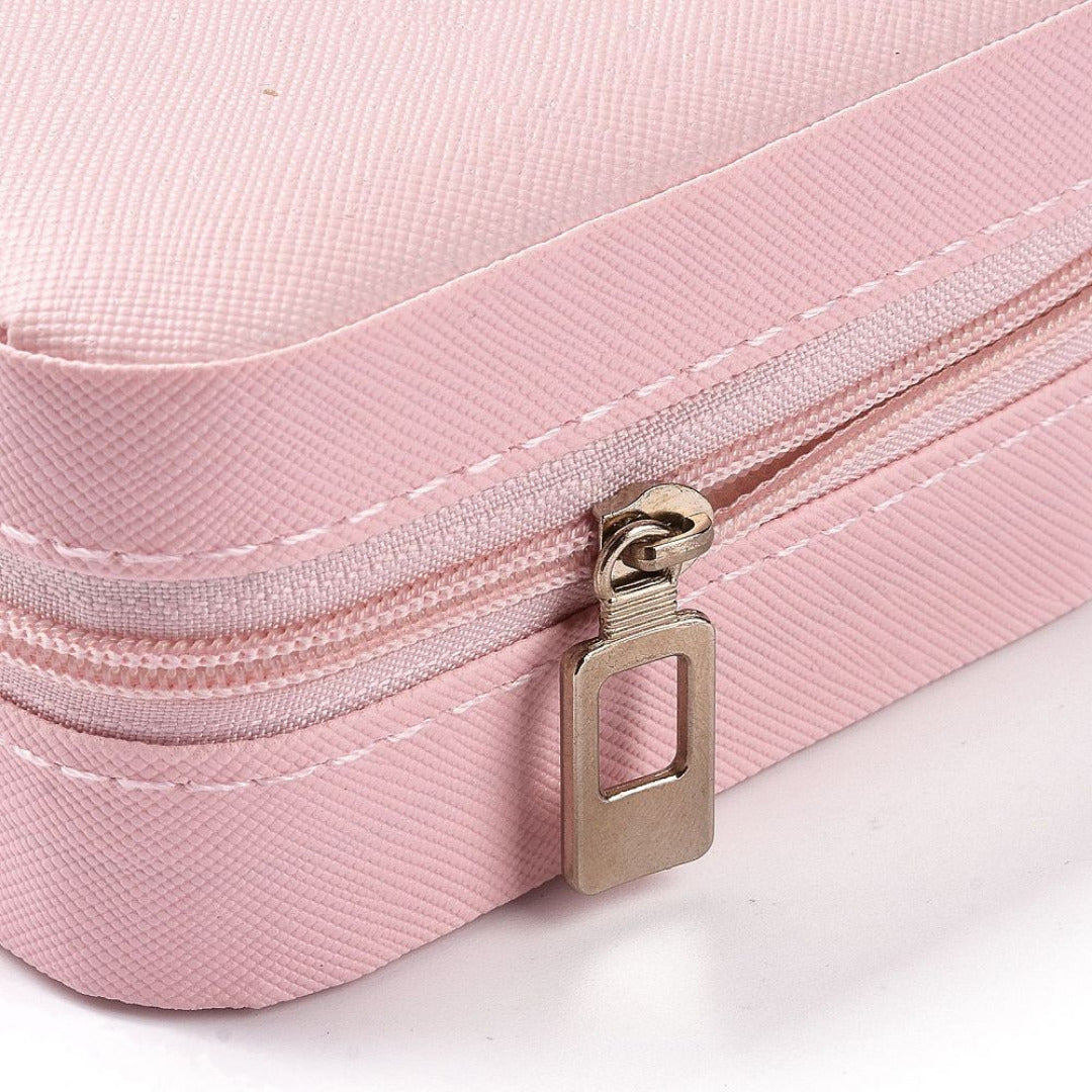 Close up of the pink jewellery box corner showing the textured finish, stitching and metal zip pull.