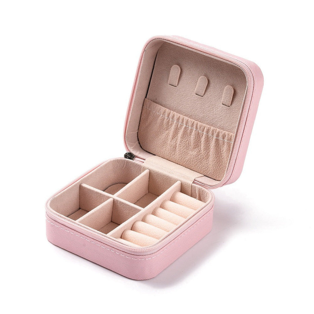 Pink zip up jewellery box open to show the lined interior with ring rolls, small compartments and hooks for earrings.