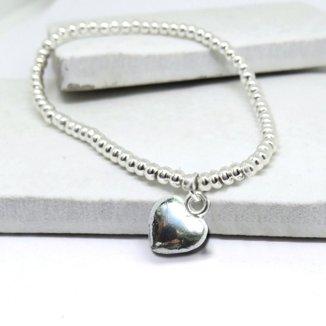 Close up of the silver plated puff heart charm on the beaded stretch bracelet