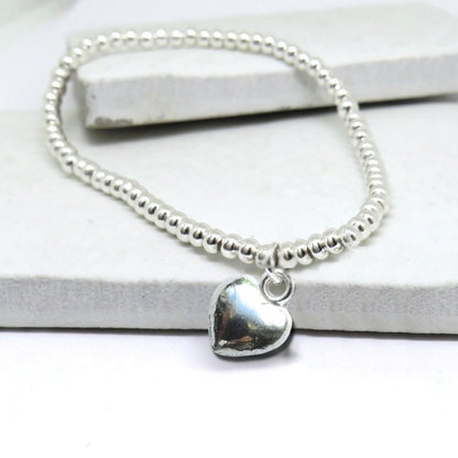 Close up of the silver plated puff heart charm on the beaded stretch bracelet