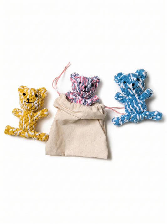 Three colourful dog toy ropes in pink, blue, and yellow, each shaped like a bear, displayed with a beige travel pouch 